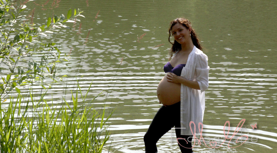 Fröhlich lachend schaut die junge Schwangere in die Kamera
