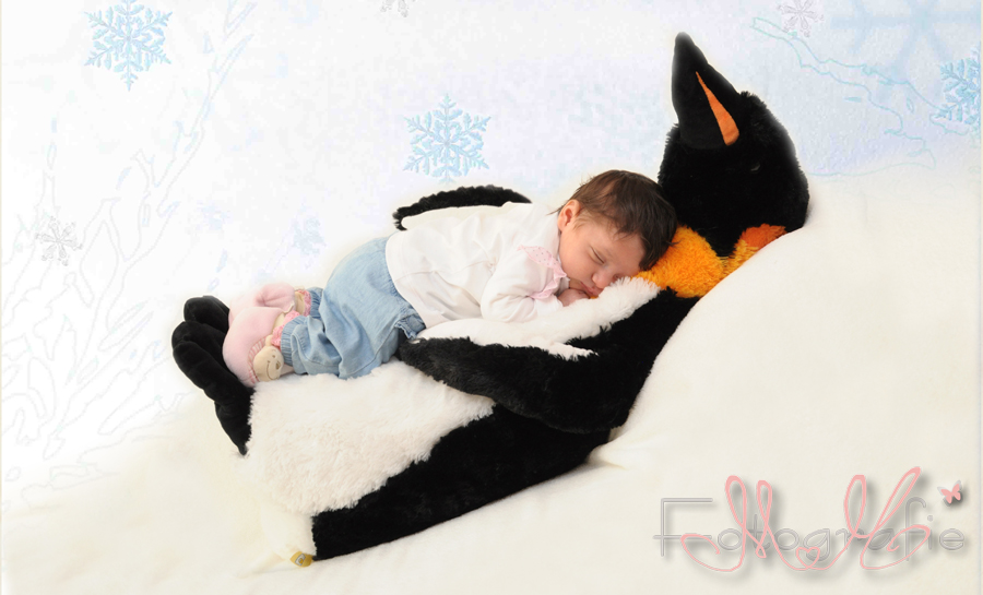 Kleines Baby liegt auf einem großen Pinguin