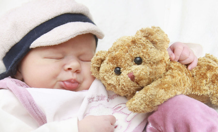 kleines Mädchen mit einem Teddybär im Arm.