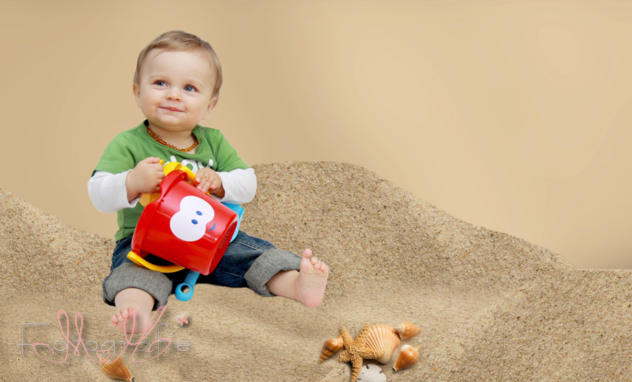Babyfoto eines kleinen Jungen, der im Sand spielt. 