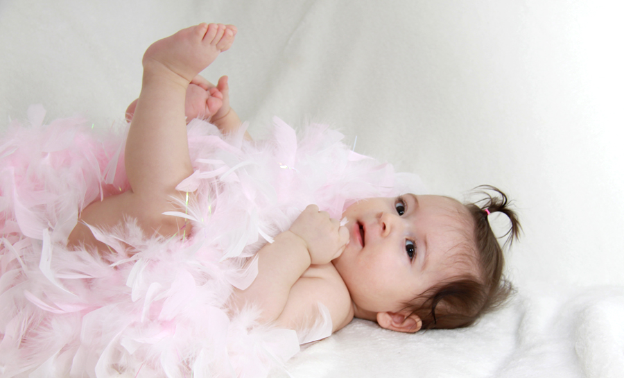 Ein kleines Baby mit einer rosa Federboa.