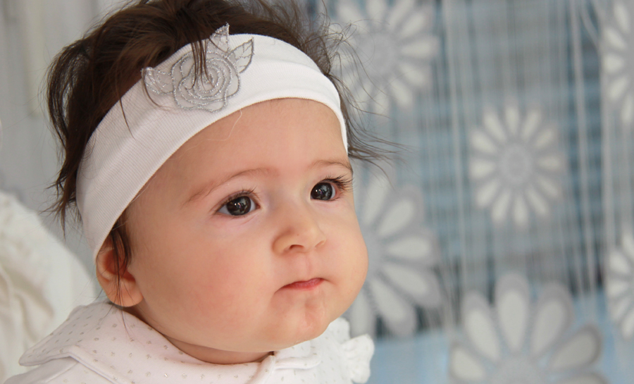 Portrait eines sechs Monate alten kleinen Mädchens mit einem weißen Stirnband.
