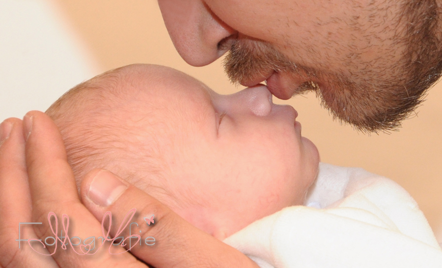 Der Papa gibt seinem kleinen Baby einen Kuss auf die Nase
