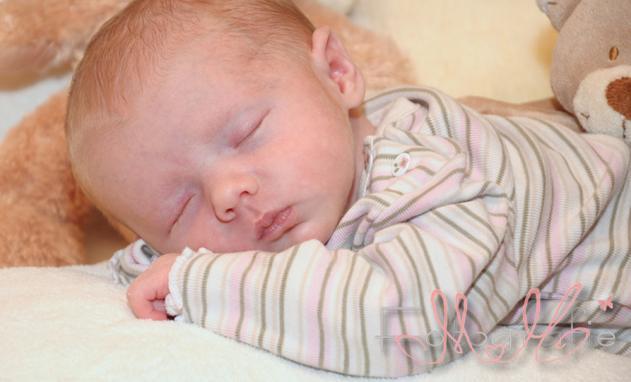 Ganz kleines Neugeborenes Baby liegt auf dem Bauch und schläft.
