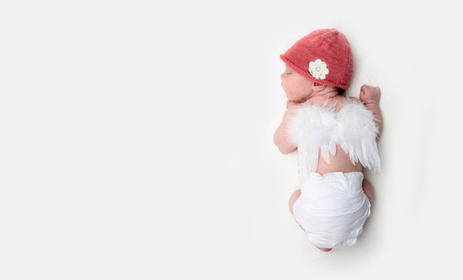 neugeborenes Baby mit Mütze und Engelsflügeln