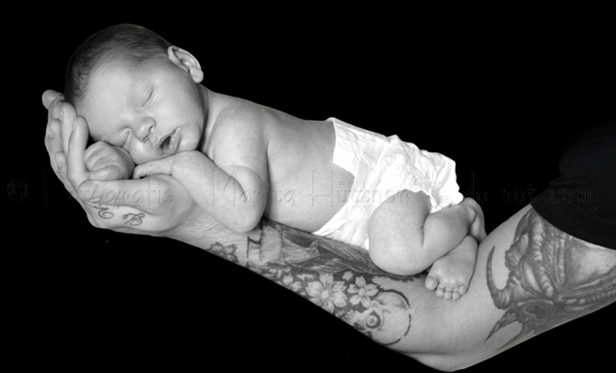 Schwarzweißfoto - ein kleines Baby auf dem Arm seines Vaters
