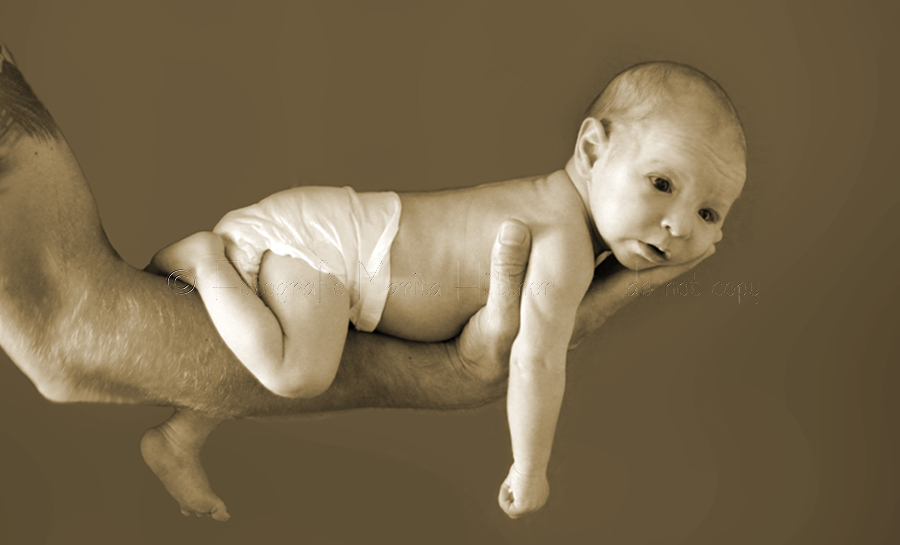 Foto in Sepia - ein süßes Baby auf dem Arm seines Vaters