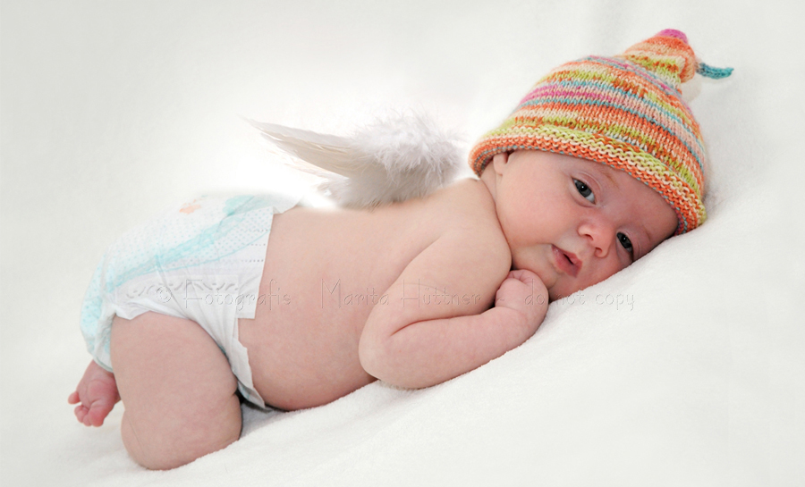8 Wochen altes Baby mit Engelsflügeln und Strickmützchen