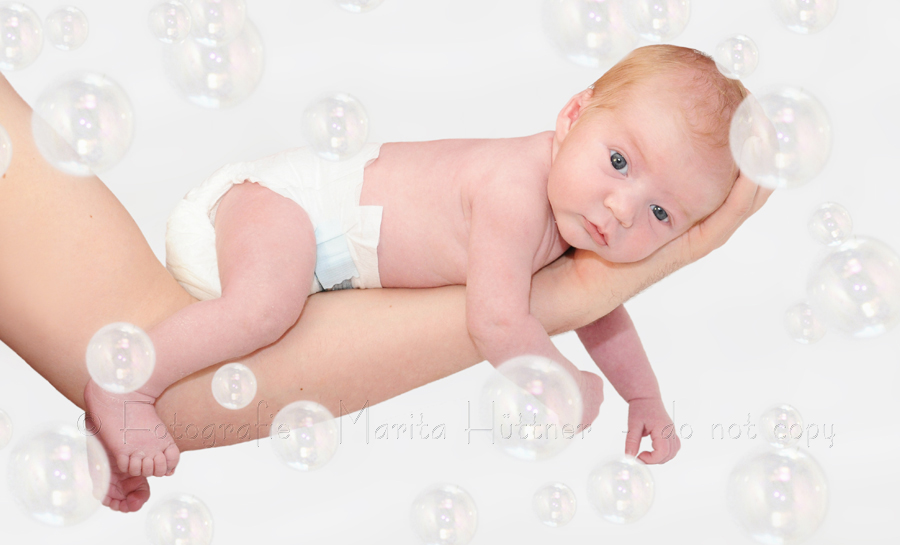 Baby auf dem Arm seines Vaters - Babyfoto mit Seifenblasen