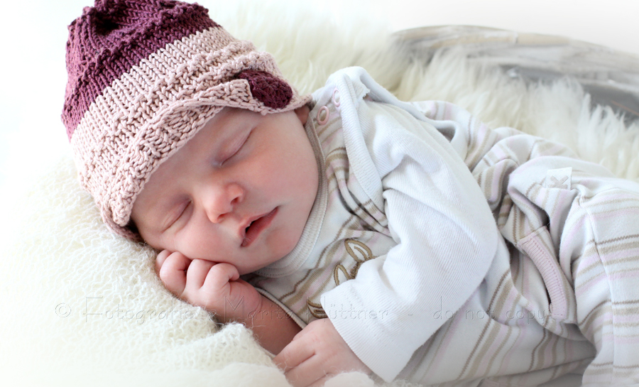 kleines Baby Mädchen mit Strickmütze - Babyfotografie
